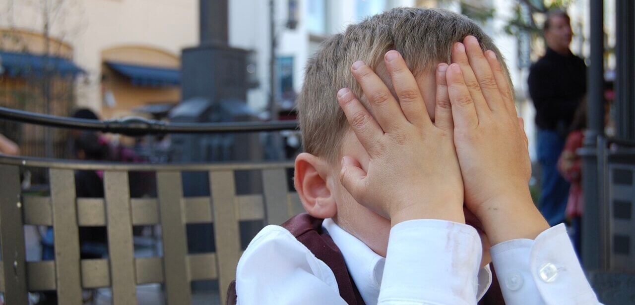 boy hiding behind hands