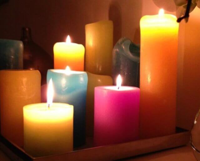 Colorful candles glowing warmly on a tray, symbolizing energy and living in color rather than burning out