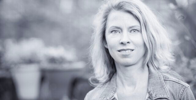 Iris van Ooyen, life navigation mentor, standing outdoors — here to help you notice the signs before the wake-up cal